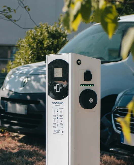 Borne de recharge intelligente et connectée Nexteneo devant un véhicule électrique