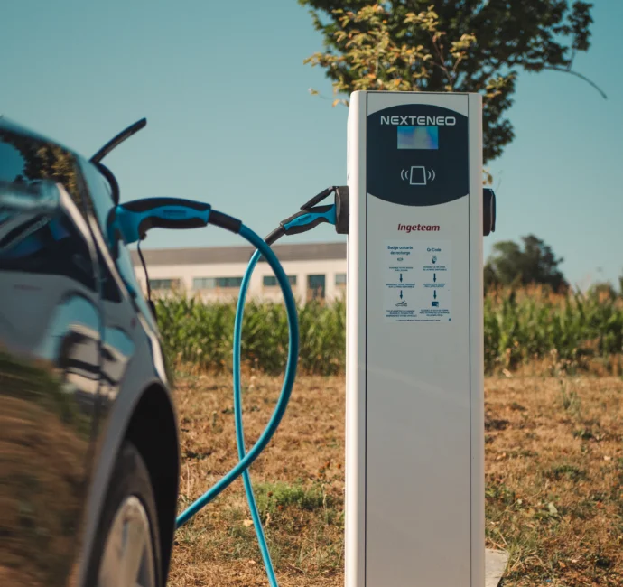 Véhicule électrique en train de se charger à l'aide d'une station Nexteneo sur un parc de bornes de recharge. La technologie Ingeteam est mise en évidence sur la borne connectée.