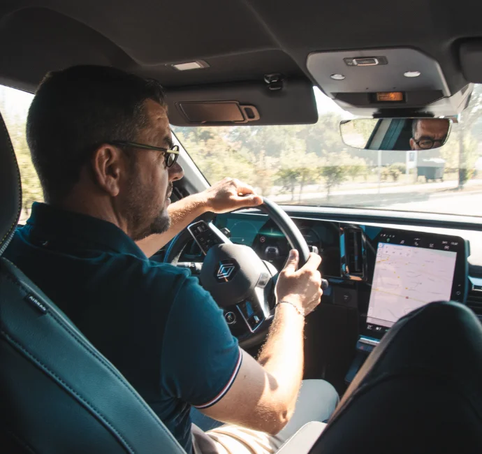 Conducteur dans une copropriété au volant d'une voiture électrique cherchant une borne de recharge connectée Nexteneo