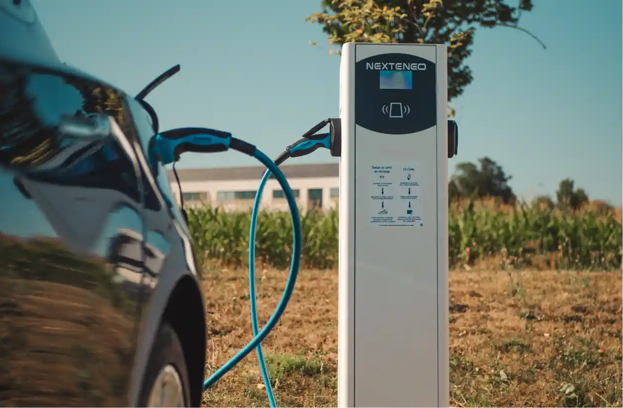 Véhicule hybride en train de se recharger à l'aide d'une borne Nexteneo sur un parc de bornes de recharge. Les conseils d’utilisation sont mise en évidence sur la borne.